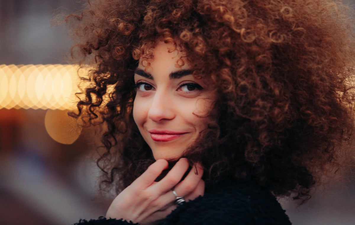 Woman with fine curly hair smiling in natural light