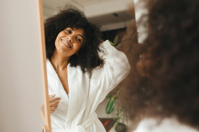Woman with curly hair following her hair care routine at home